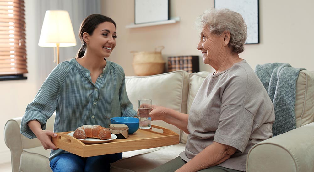 daughter serving senior mother dinner on tray