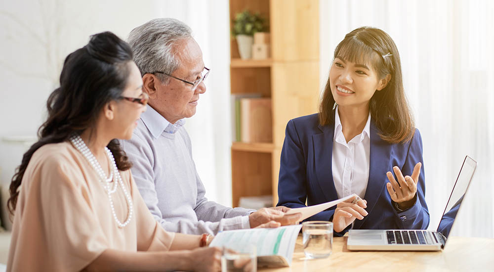 Senior couple speaking with estate planner at kitchen table