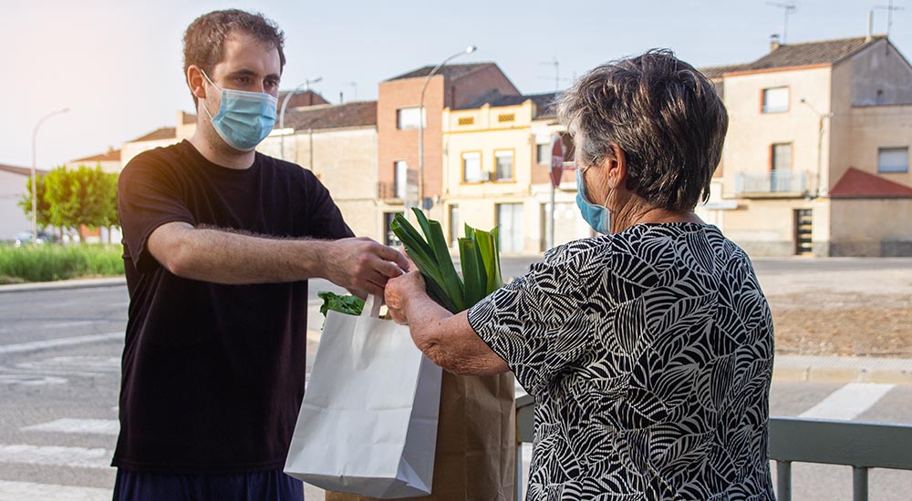 male delivers groceries to elderly woman