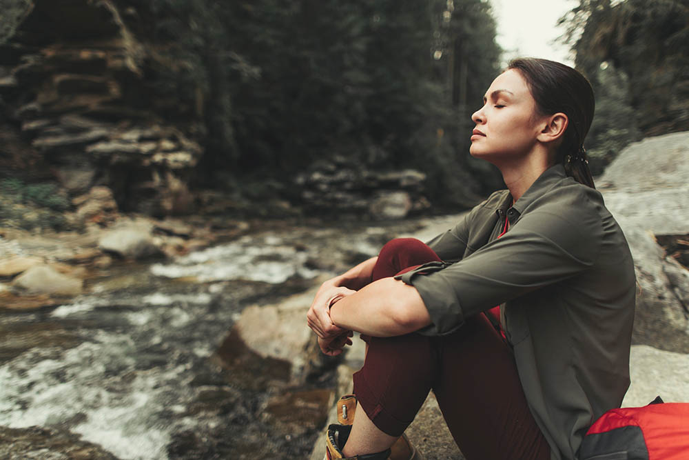 woman meditating at creekside