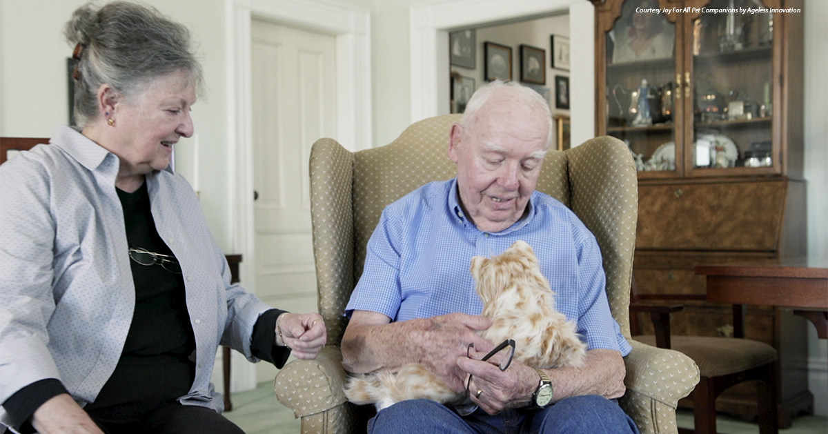 An animatronic cat is presented to an elderly man.