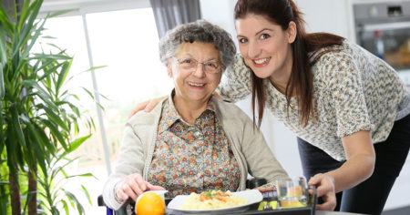caregiver serving meal to elderly woman