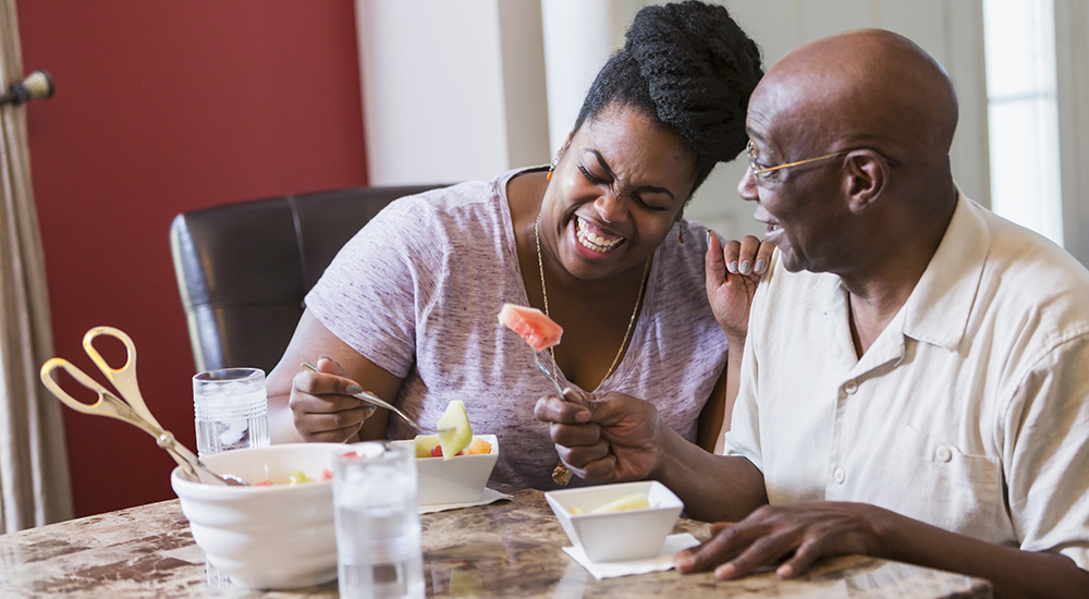 adult daughter helping elderly father to eat