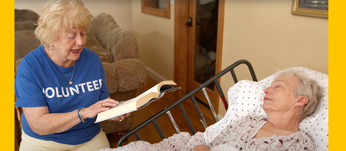 volunteer reading to patient at the bedside
