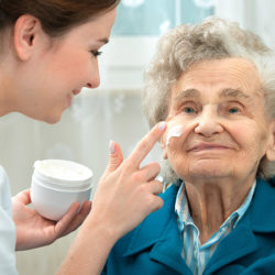 caregiver applies face lotion to patient
