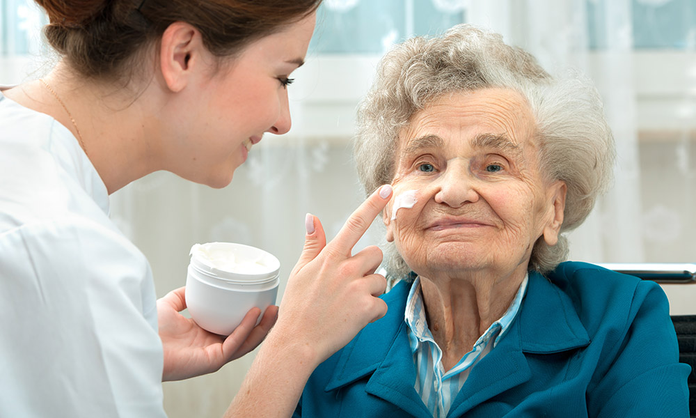 caregiver applies face lotion to patient