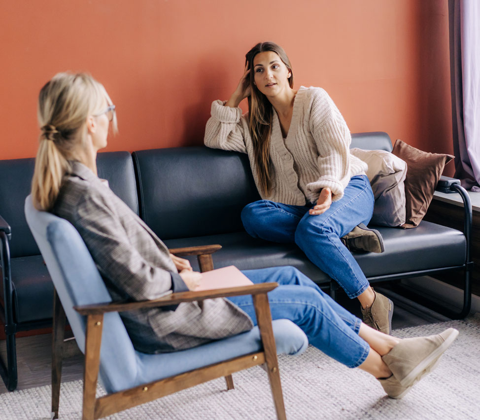 Two people talk while sitting down.