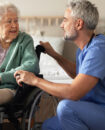caregiver talking with elderly woman in wheelchair