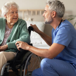 caregiver talking with elderly woman in wheelchair