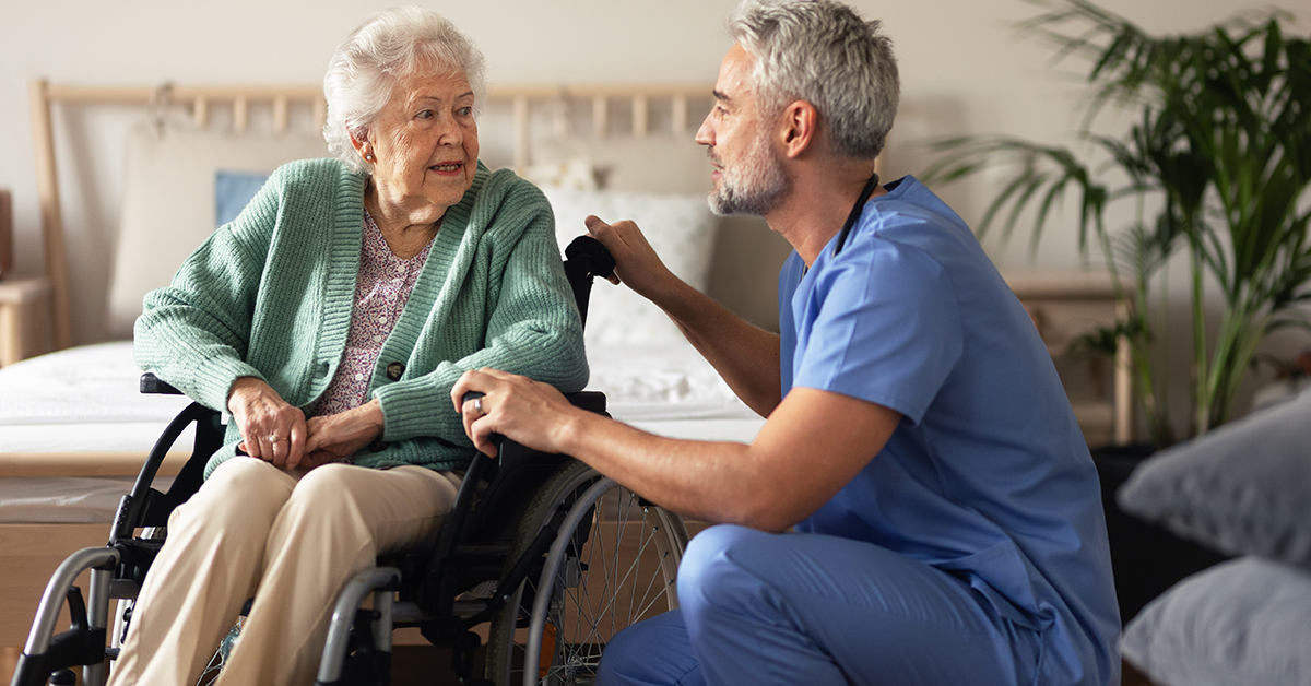 caregiver talking with elderly woman in wheelchair 